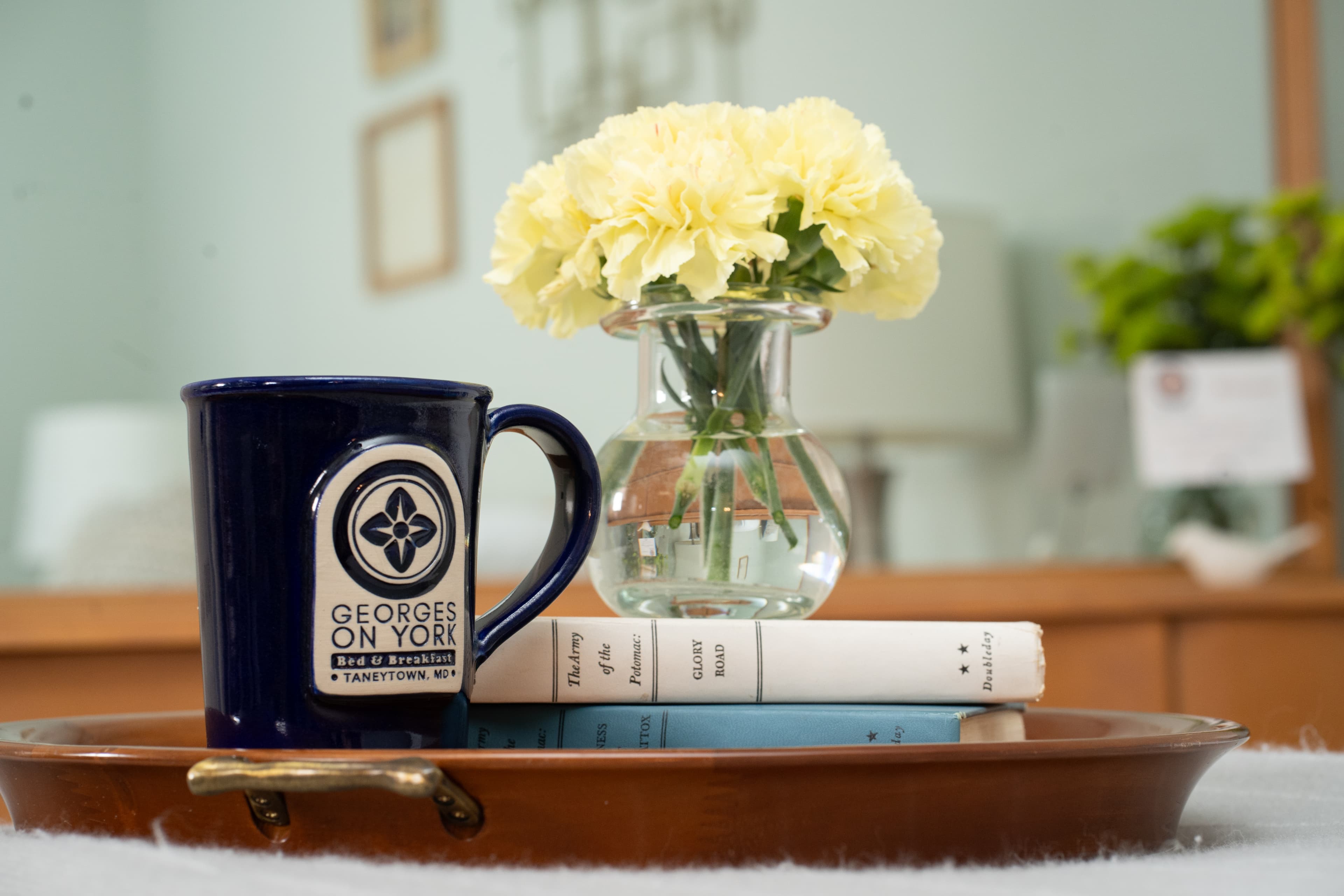 Books, coffee and flowers on the king bed in Baumgardner Room