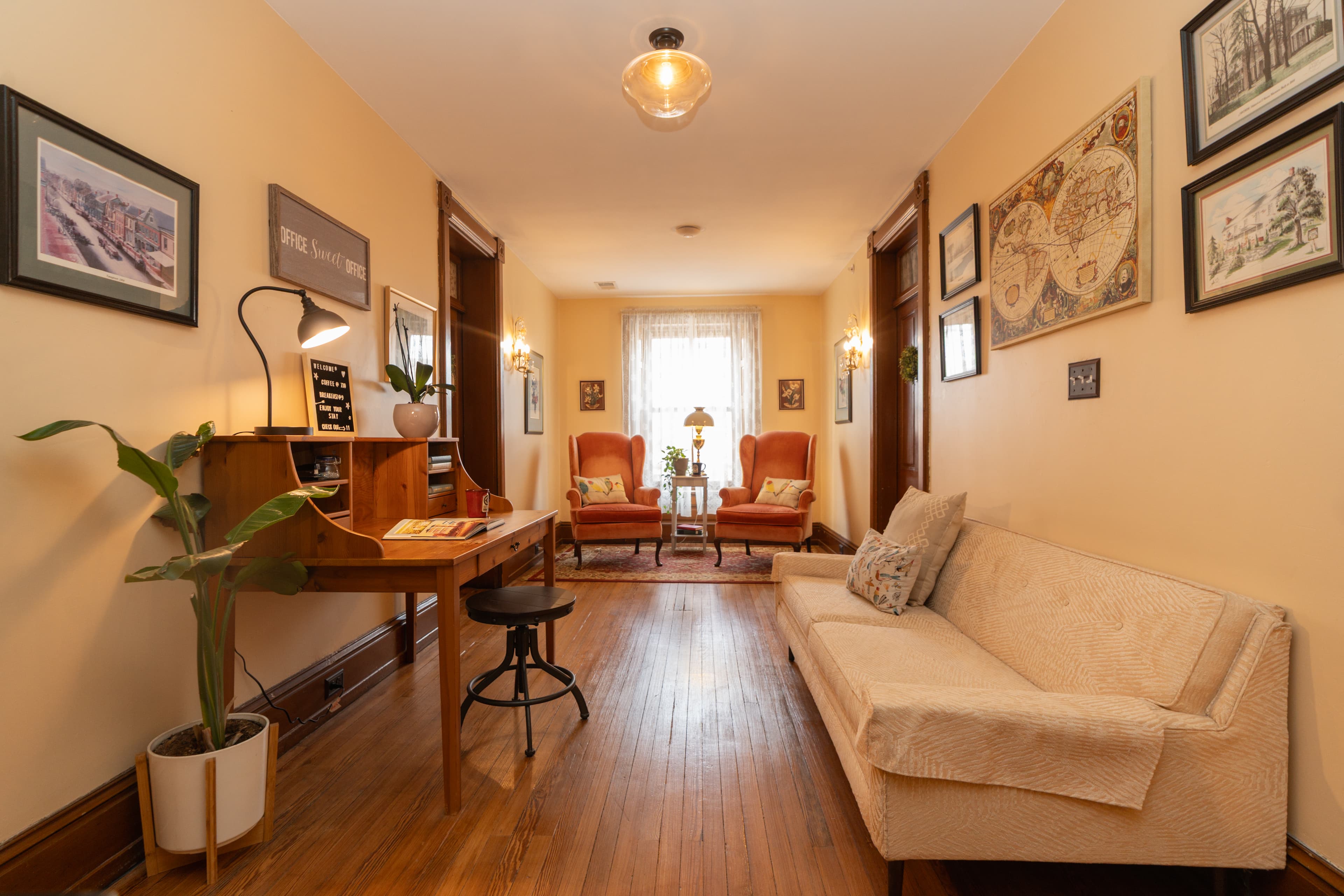 Additional seating area and desk outside the Wilt Room on the second floor with peach couch, two pink wingback chairs and a desk