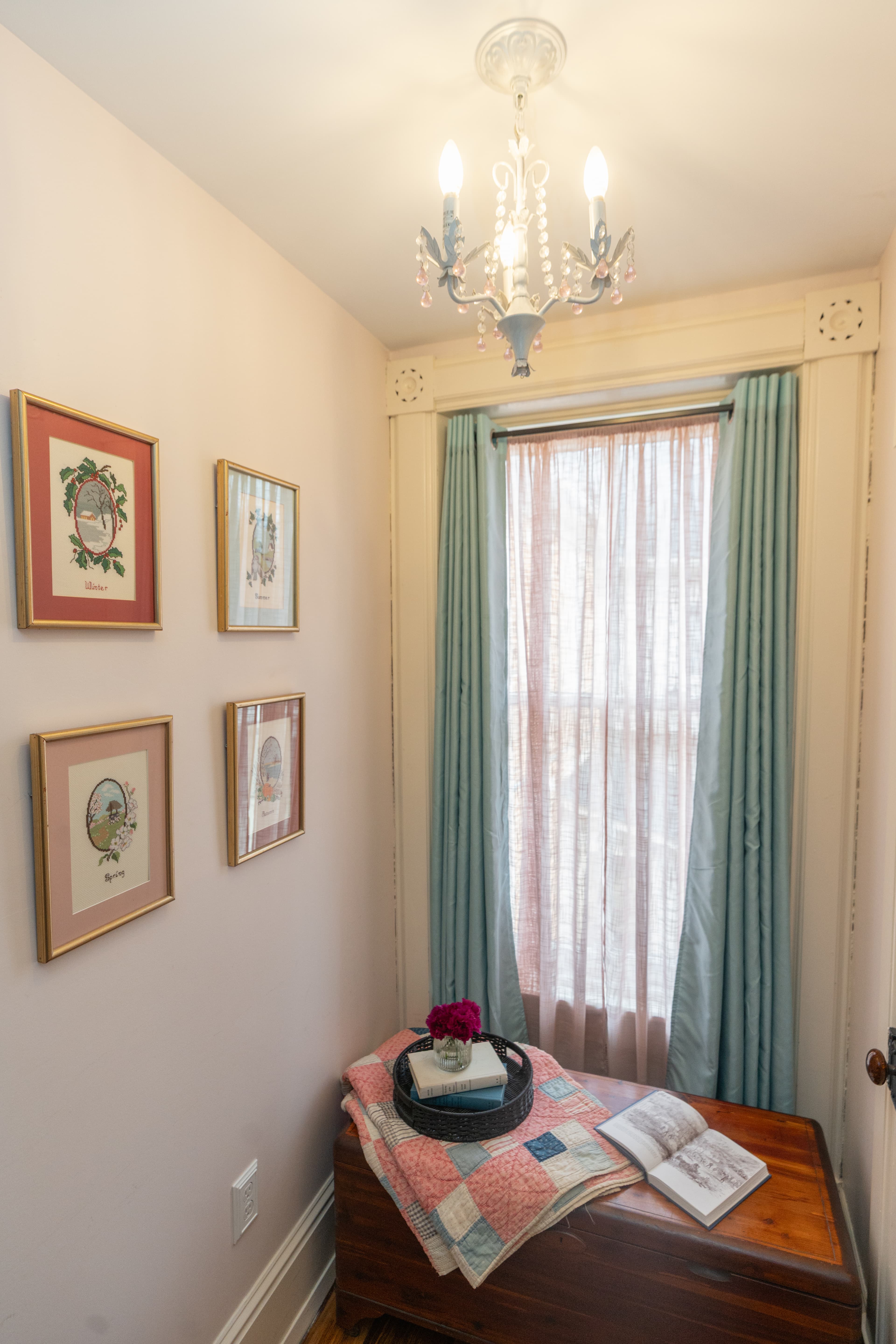 Nook with vintage needlepoints depicting the four seasons, trunk and blanket for reading, closet door to the right