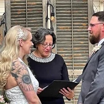 A bride and groom stand before an officiant during their wedding ceremony.