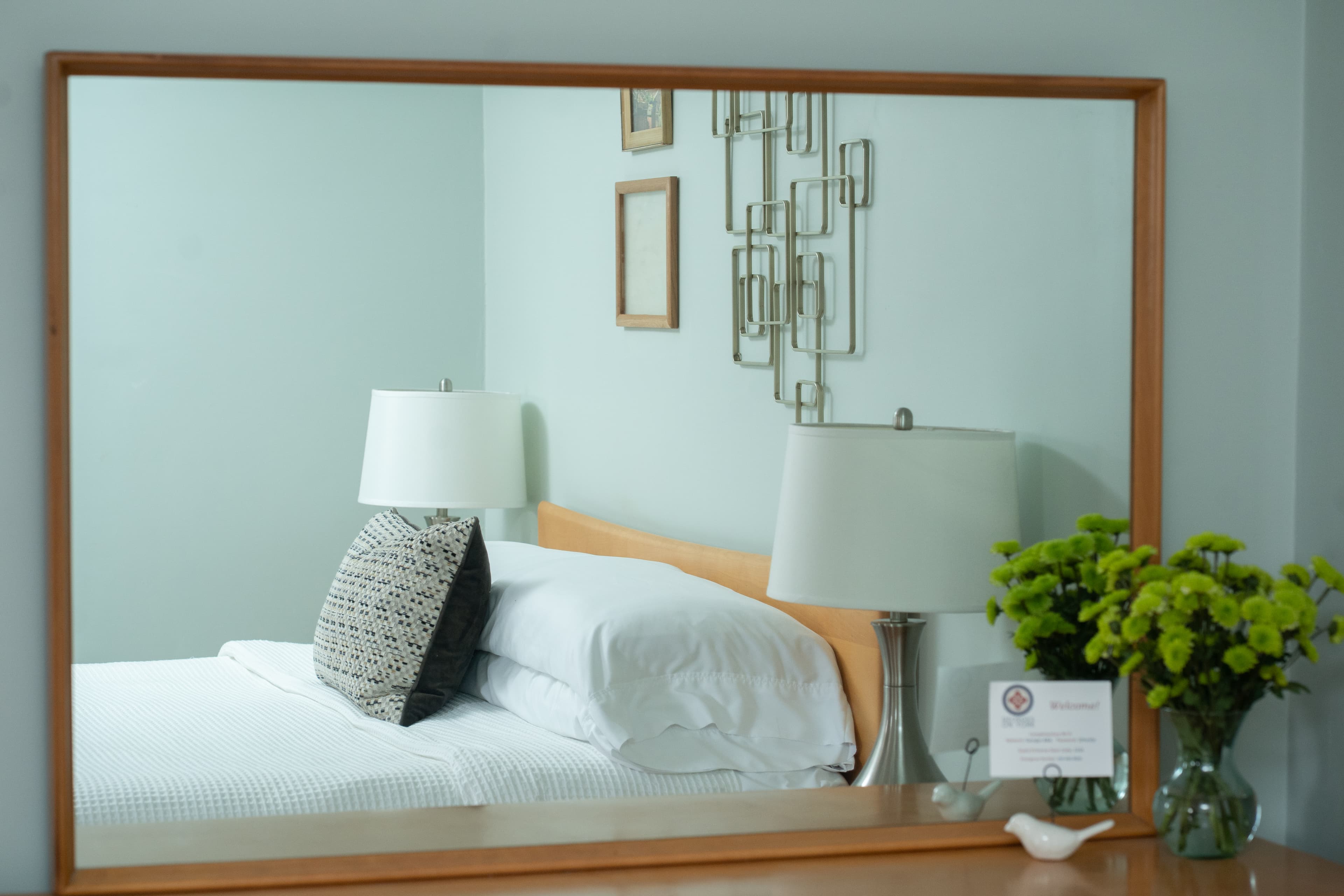 Looking back at the room through the mirror on the dresser with a focus on the bed