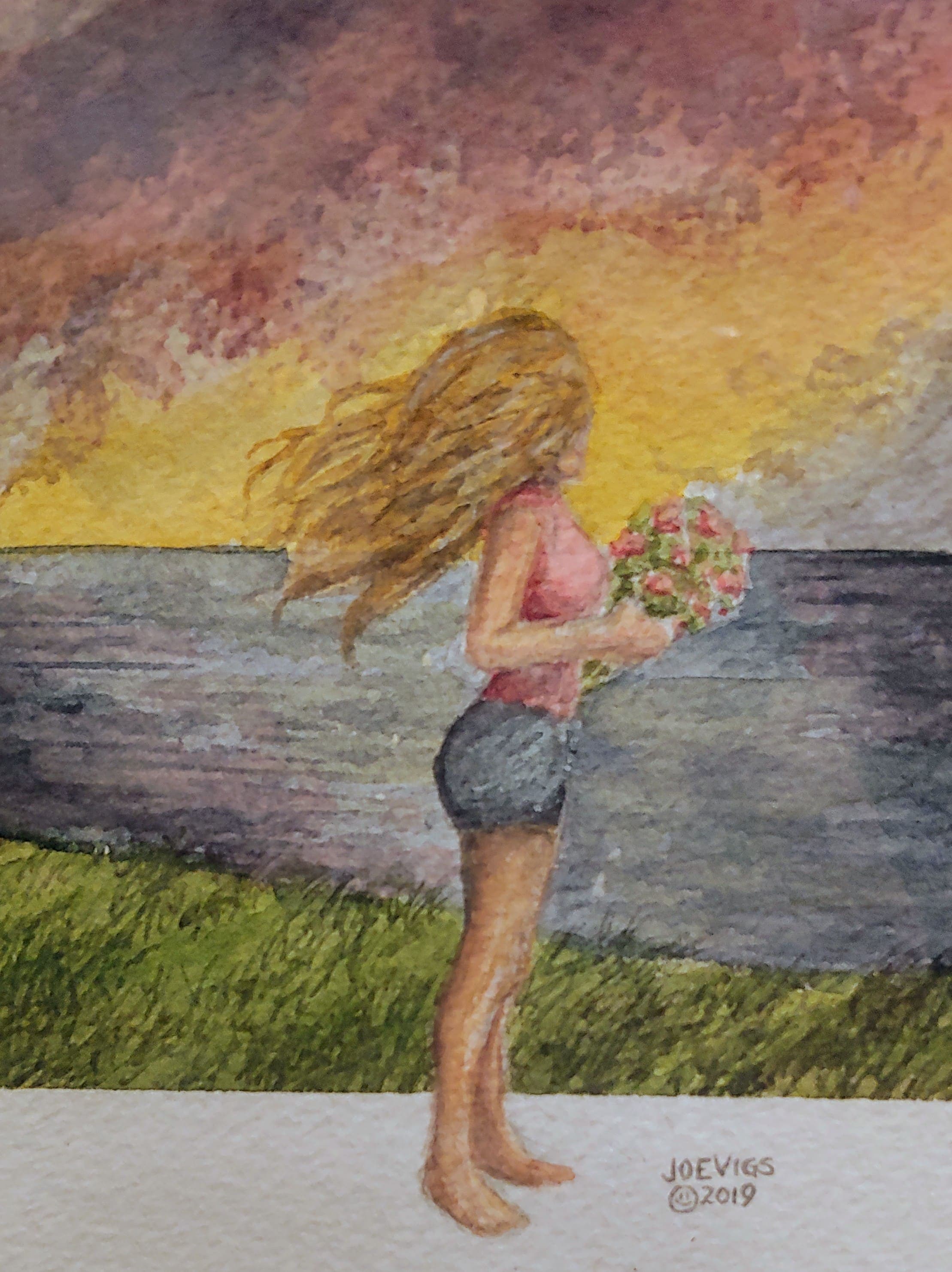 A woman with long hair stands by the water at sunset, holding a bouquet of flowers.