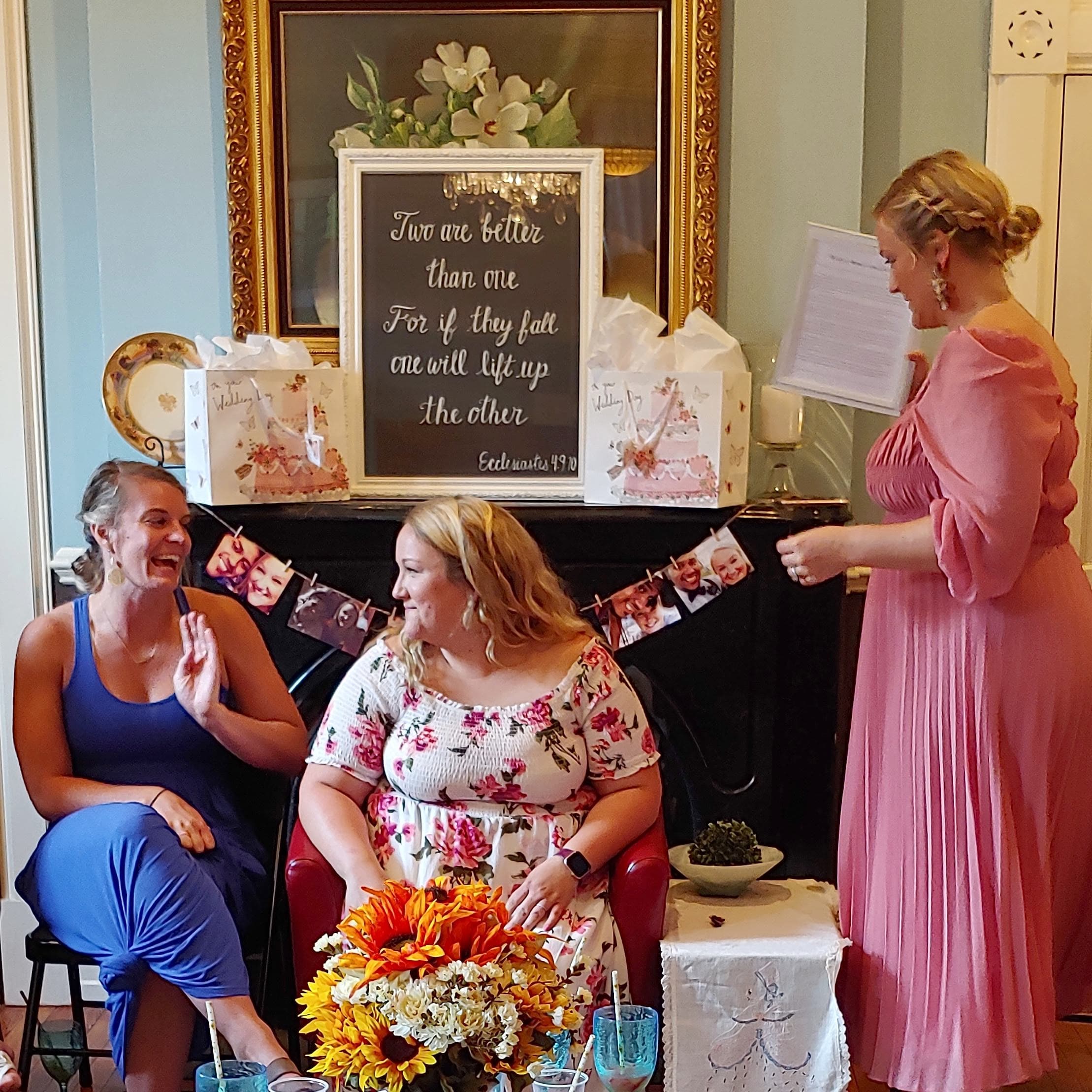 Three women share laughter and conversation in a cozy room decorated for a gathering.