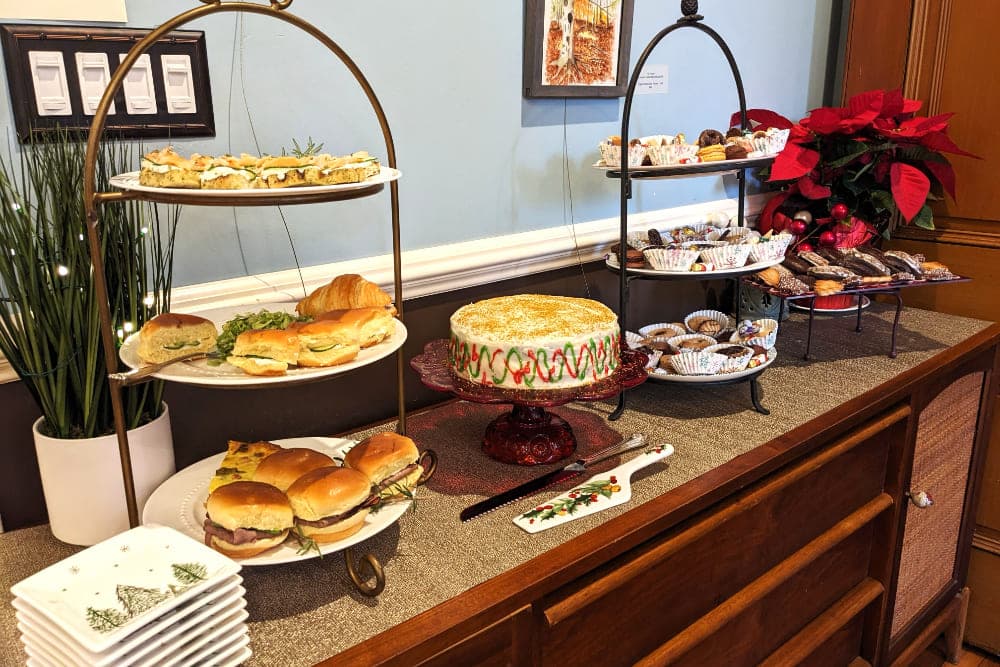 A festive display of assorted sandwiches, pastries, and a decorated cake on a wooden table.