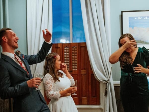 A joyful couple and a guest celebrate with drinks in an elegantly decorated room.