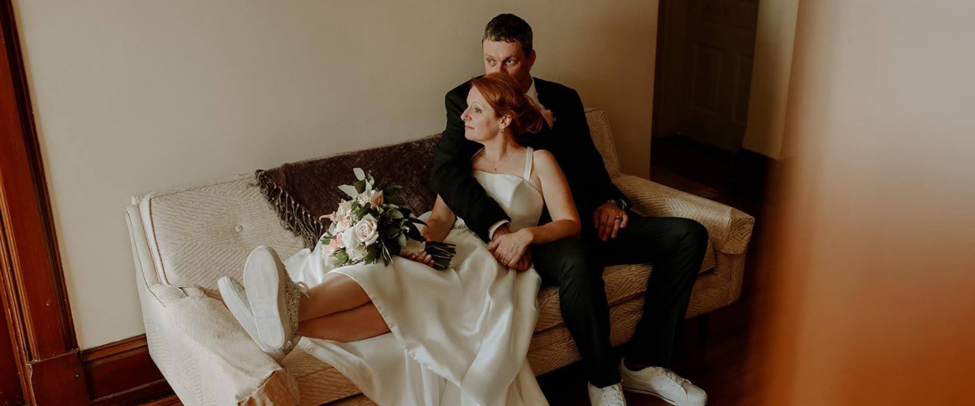 A bride and groom sit together on a couch, surrounded by wedding decor.