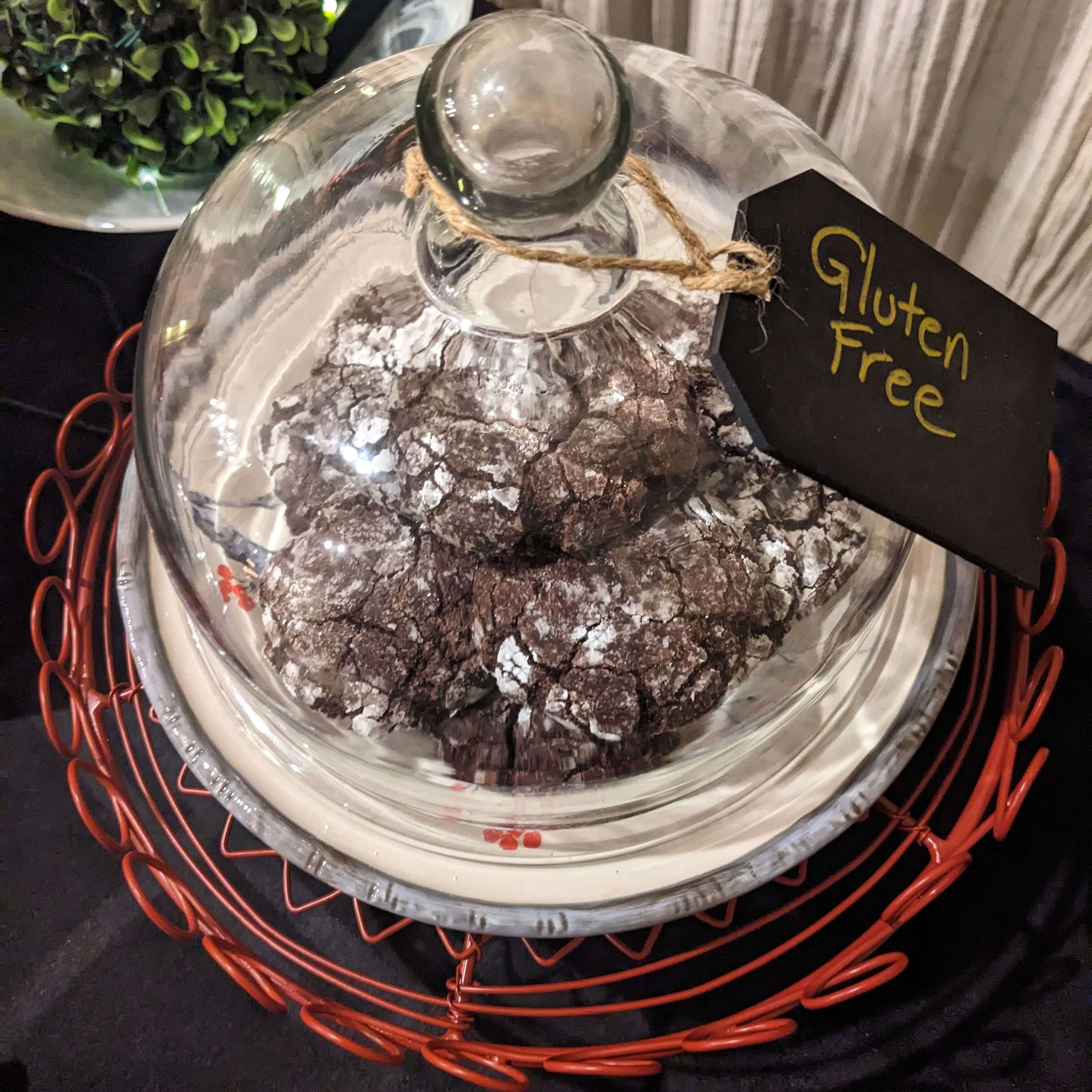 A glass dome covers gluten-free cookies on a red wire rack.
