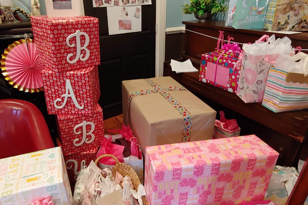 A collection of brightly wrapped gifts in a room, with some boxes spelling out "BABY."