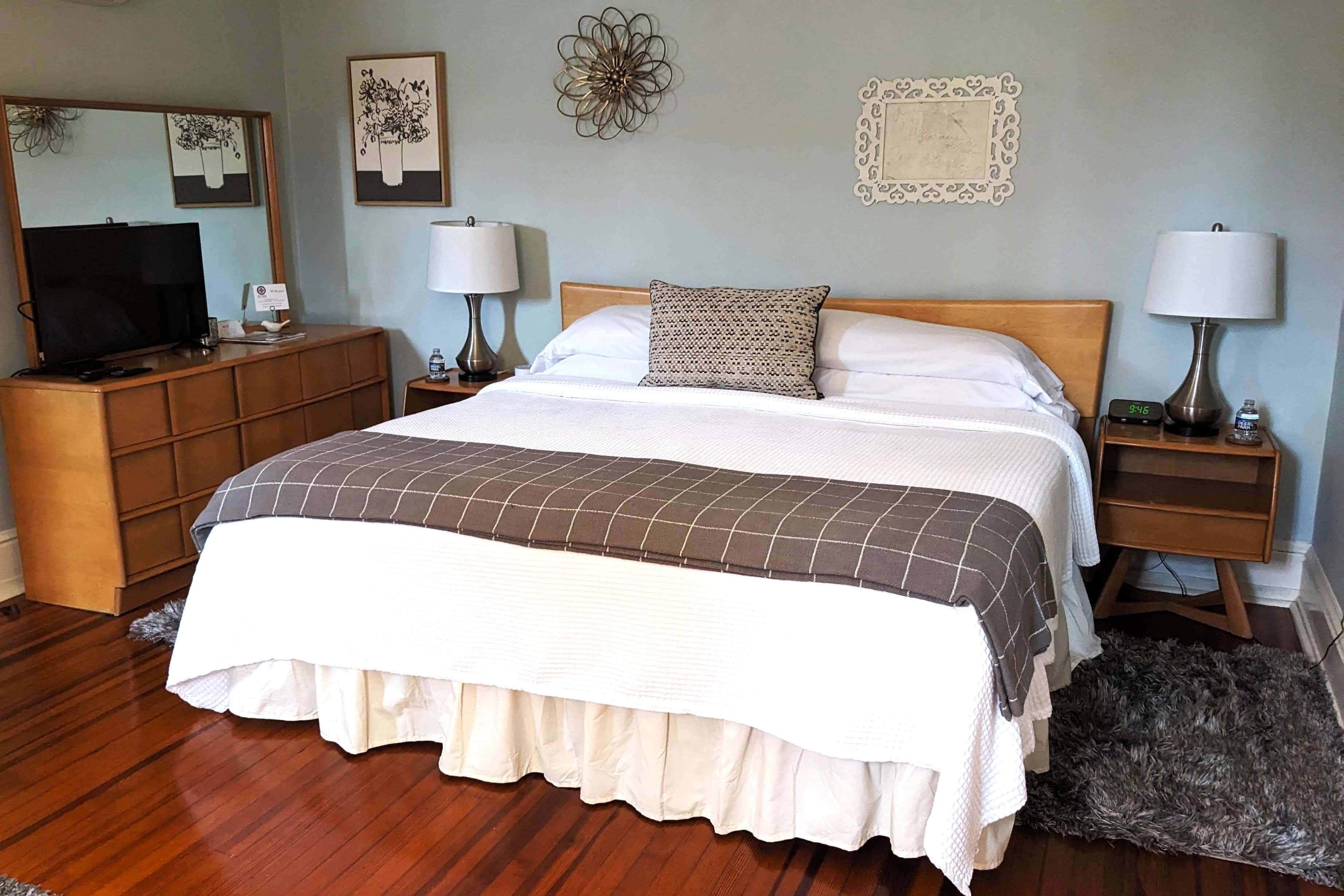A cozy bedroom featuring a wooden bed with white linens, a patterned throw, and matching bedside tables.