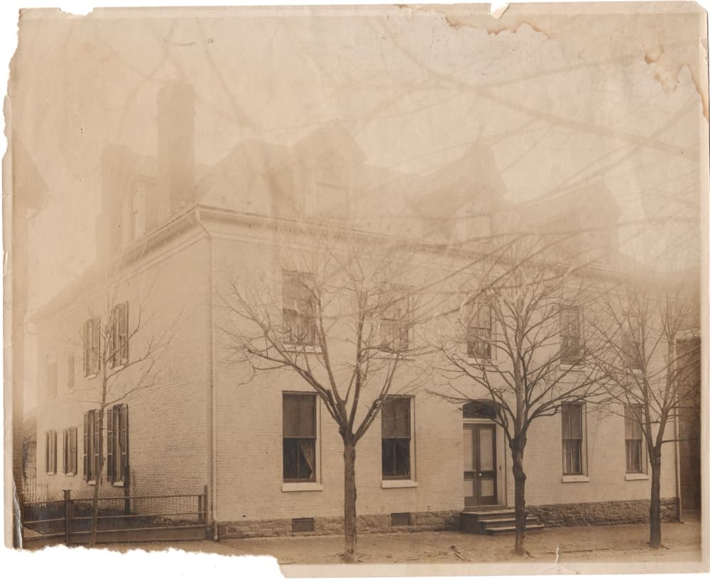 Black-and-white photo of a historic building surrounded by bare trees.