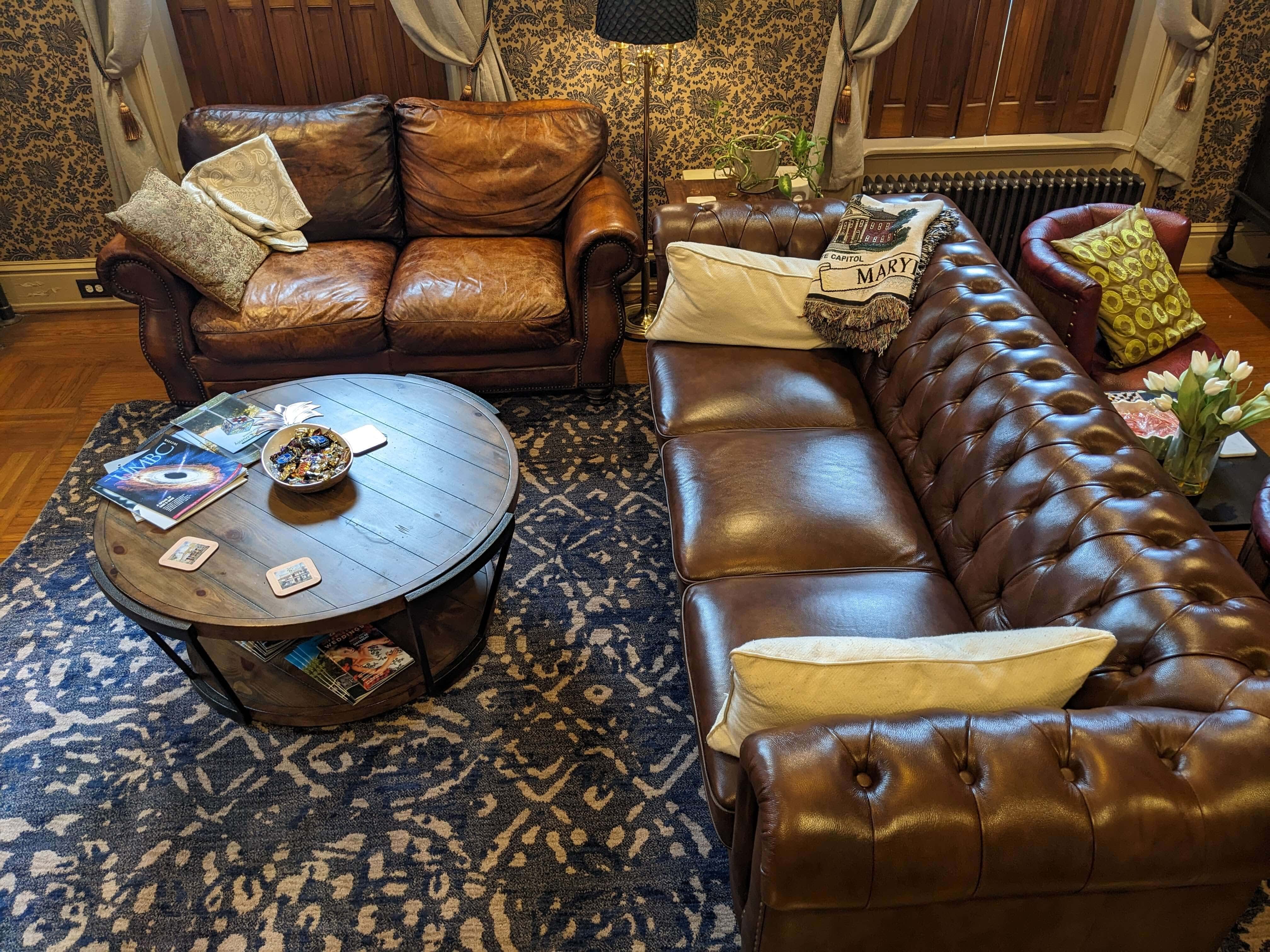 A cozy living room featuring brown leather sofas and a round coffee table on a decorative rug.