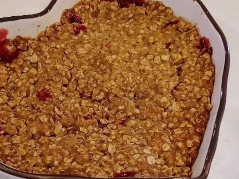 A heart-shaped dish filled with baked oat crumble topped with fruit.