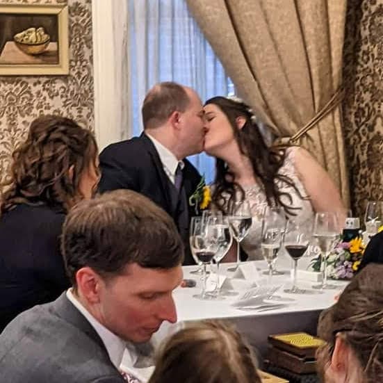 A couple shares a kiss at their wedding during a cozy reception.