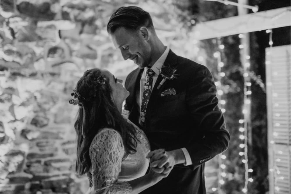 A couple shares a tender moment while dancing under soft, glowing lights at their wedding.
