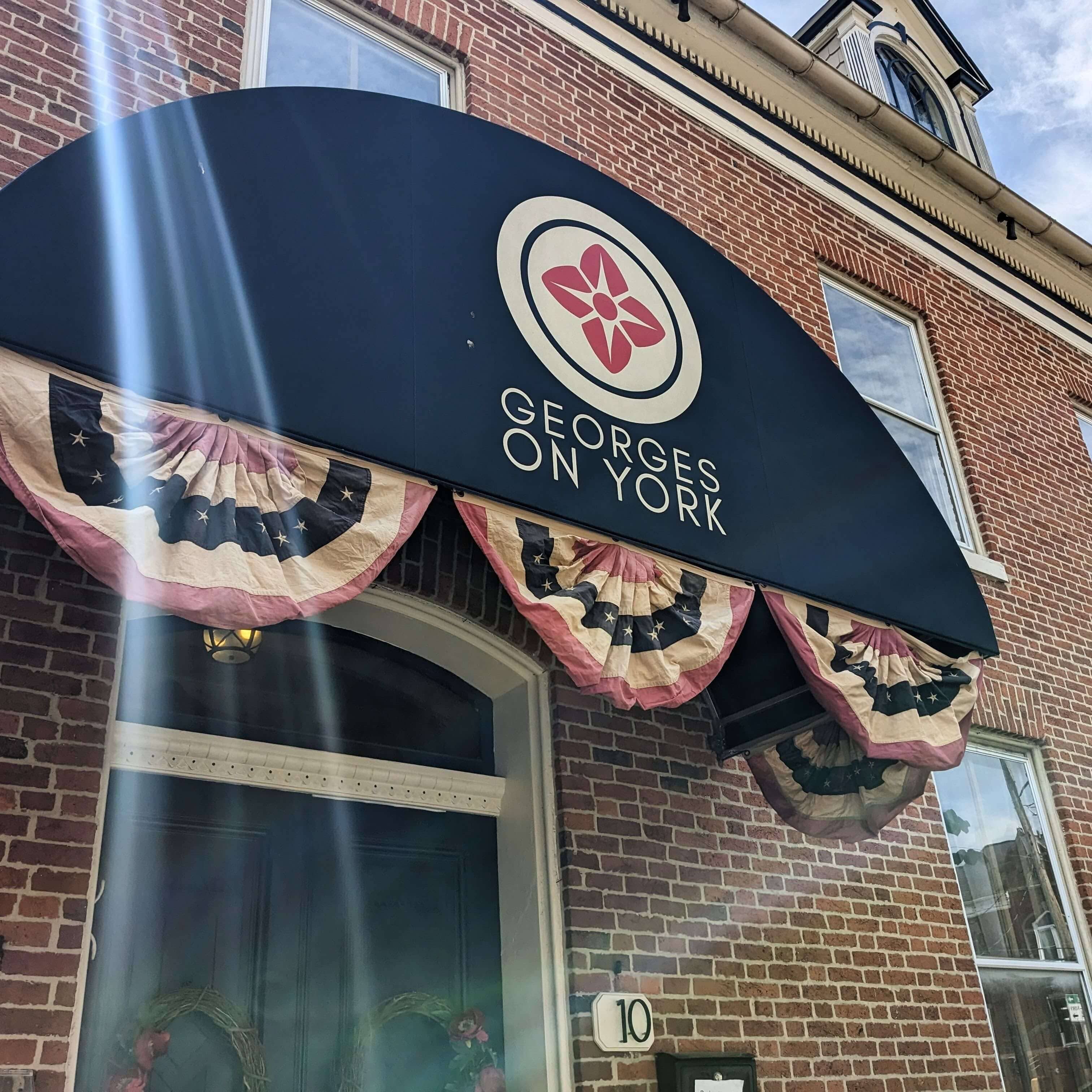 Signage for "Georges on York" with decorative bunting on a brick building.